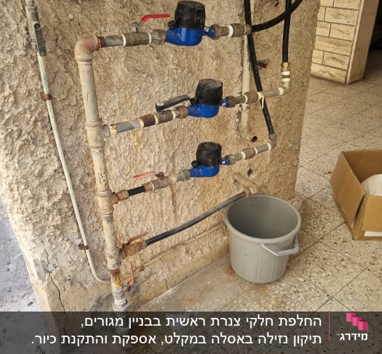 צנרת מים עם ברזים ומדי מים על קיר חיצוני